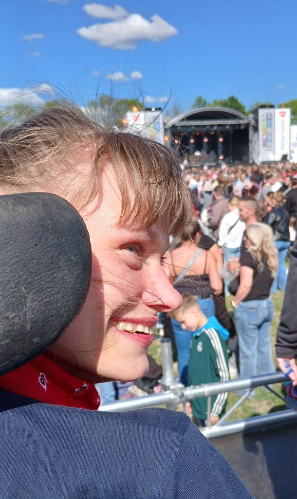 Lachende vrouw in rolstoel met op de achtergrond een concert.
